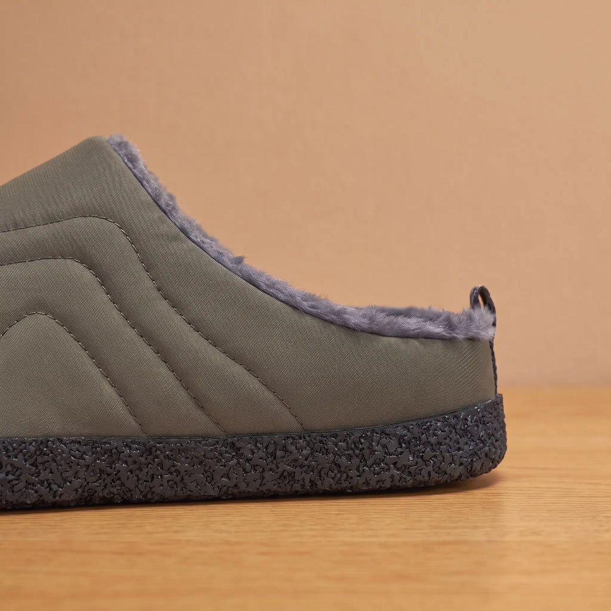 Side view of green quilted slipper showing thick speckled sole and heel pull tab