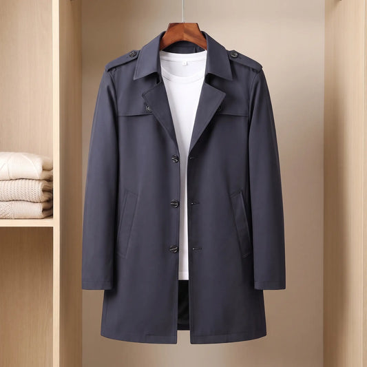 Flap Pocket Coat in navy, a slim mid-length single-breasted trench coat with epaulettes and hip flap pockets on a wooden hanger