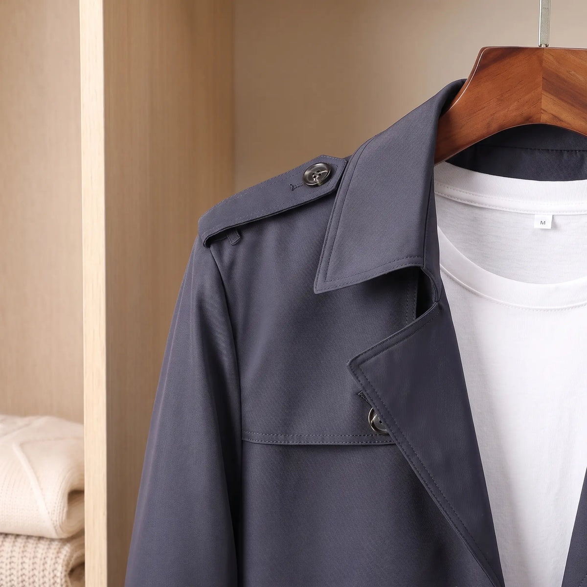 Close up of the notched lapel, buttoned throat latch and shoulder epaulette on the navy Flap Pocket Coat