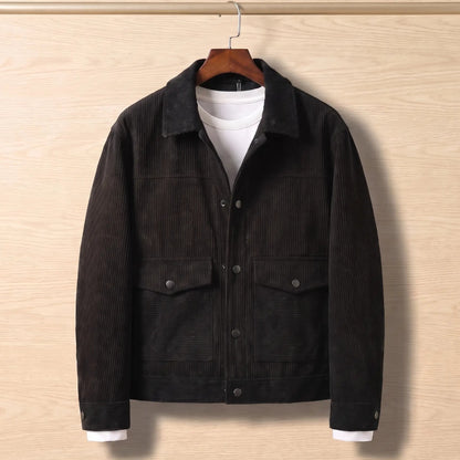 Black corduroy flap pocket jacket on a wooden hanger against a light oak wall