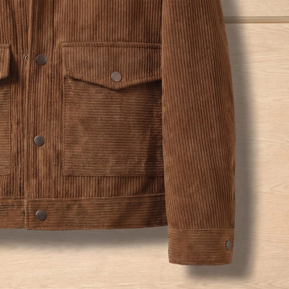 Close up of the waist flap pocket, hem band and buttoned cuff on the brown corduroy jacket