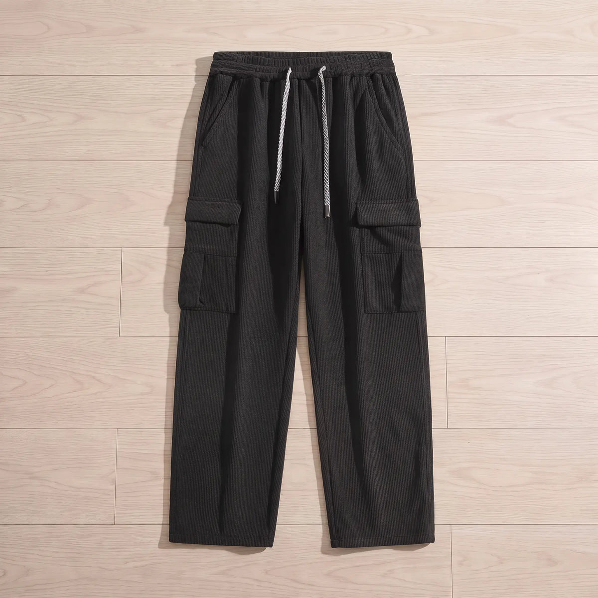 Fleece cord cargos in black corduroy laid flat on pale wooden floorboards