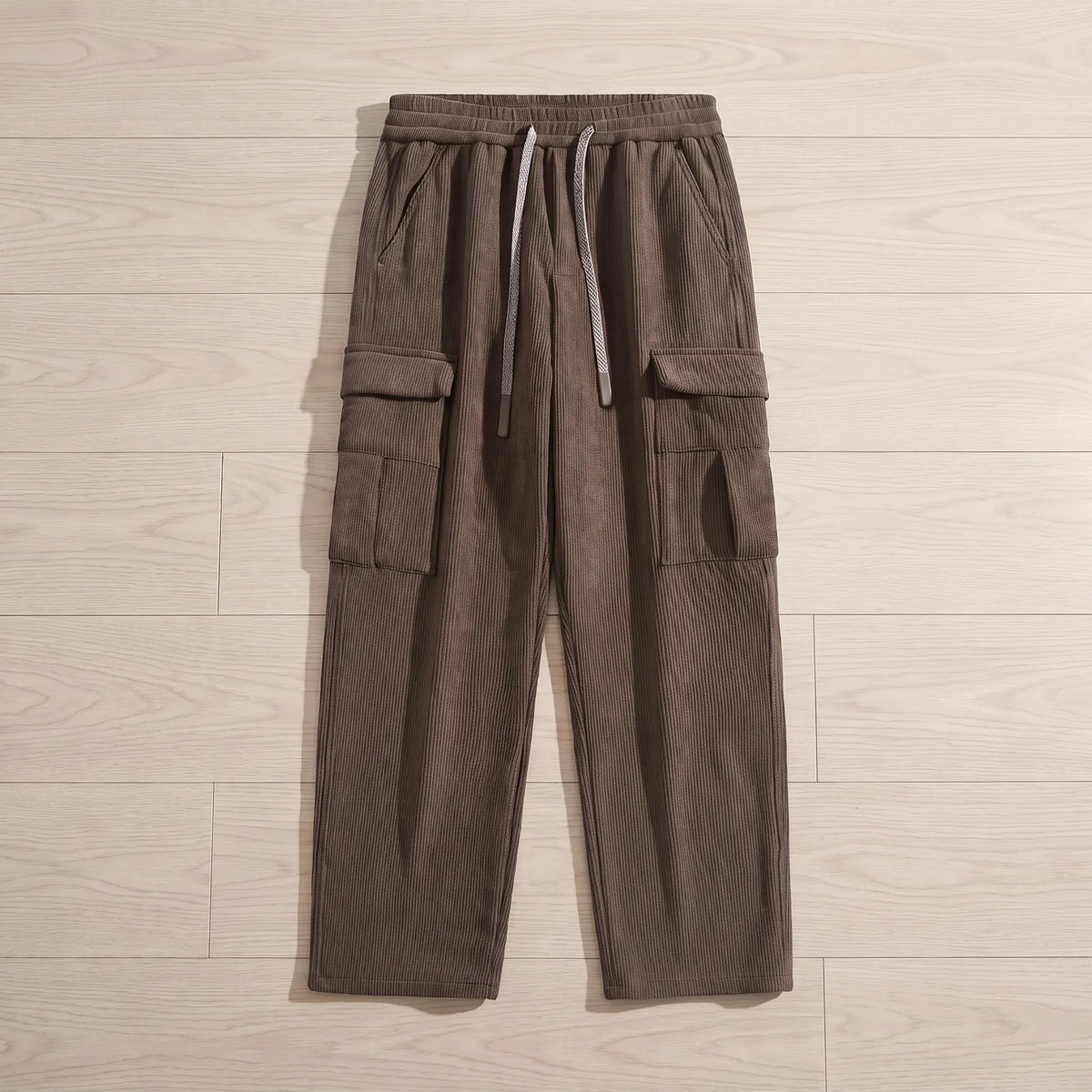 Fleece cord cargos in brown corduroy laid flat on pale wooden floorboards