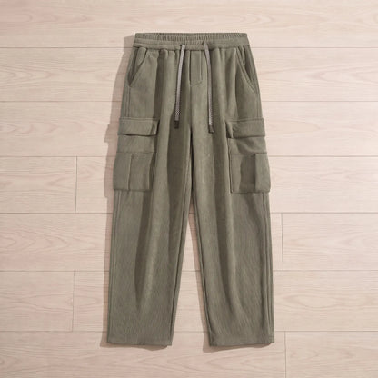 Fleece cord cargos in green corduroy laid flat on pale wooden floorboards