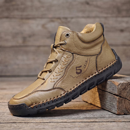 Khaki hand-stitched leather lace-up ankle boot with flexible rubber sole, side view on reclaimed oak