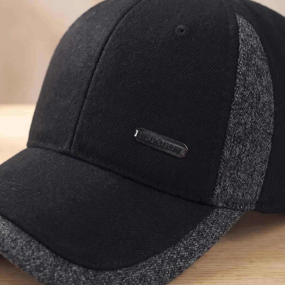 Close-up of black winter cap front panel with small metal badge and brushed fabric texture