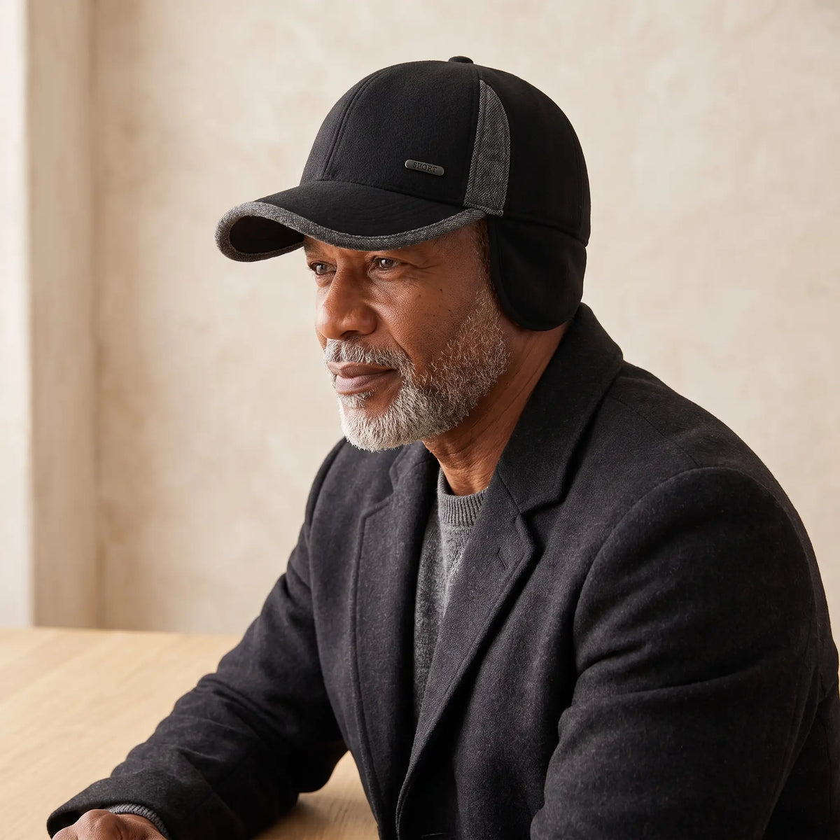 Man wearing black fold-down flap winter cap with ear flaps down and a charcoal wool coat