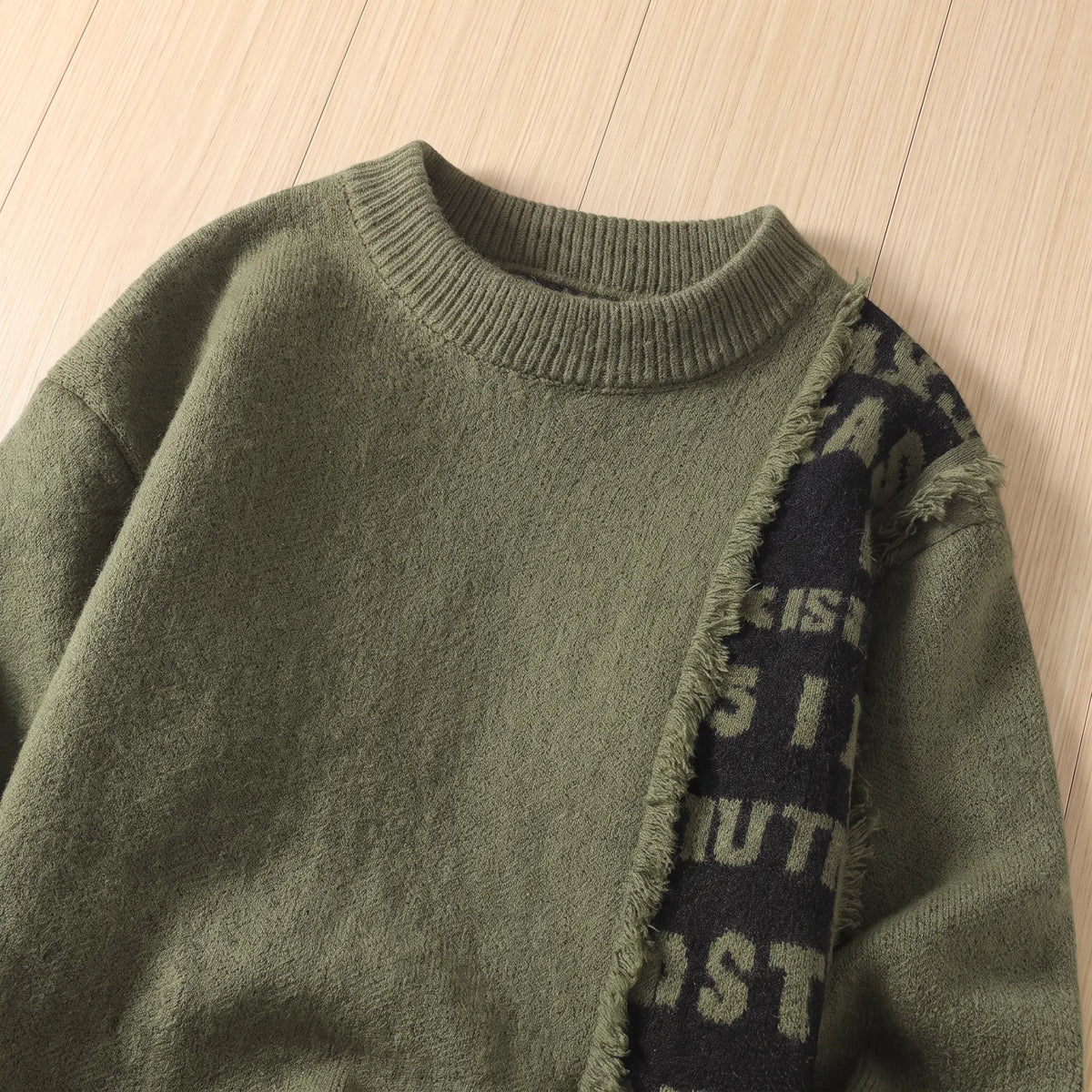 Close-up of the green frayed panel knit collar and lettered panel edge