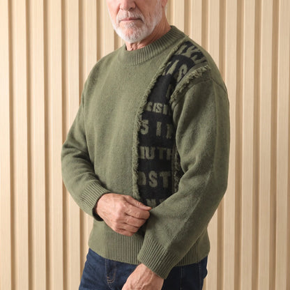 Man wearing the green frayed panel knit sweater, adjusting the cuff