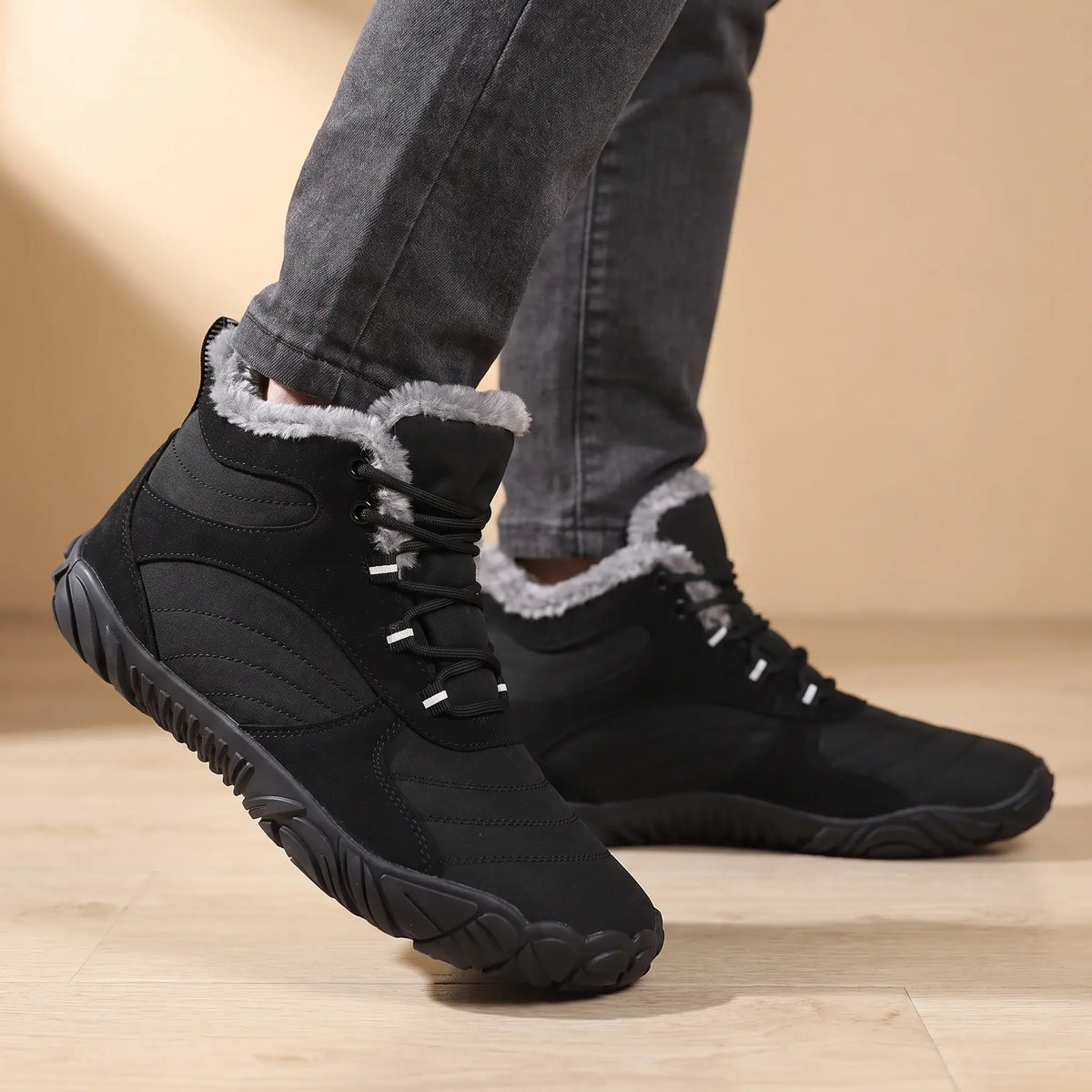 Man wearing black plush-lined winter boots with grey trousers