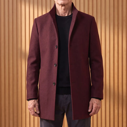 Burgundy funnel neck wool overcoat worn open over a black tee by an older man