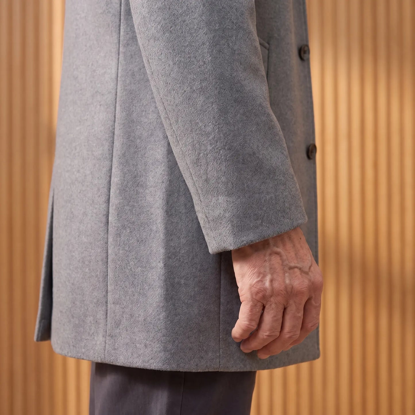 Close up of the plain sleeve cuff and straight hem of the wool overcoat