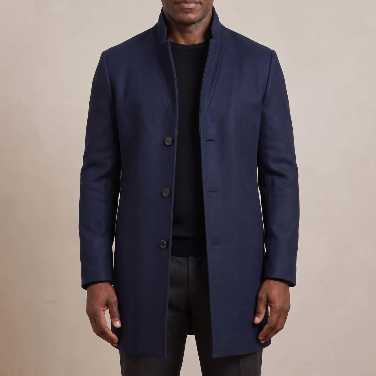 Navy funnel neck wool overcoat worn open over a black tee