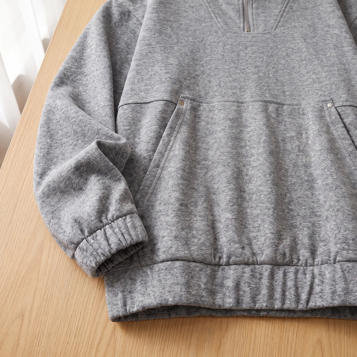Close-up of the grey heather half-zip hoodie pouch pocket, elastic cuff and hem