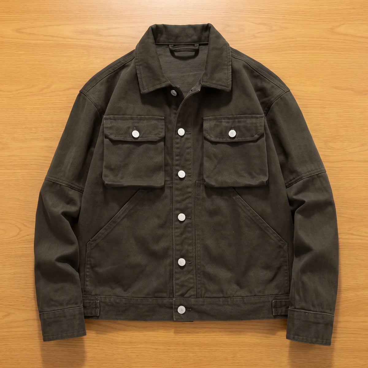 Army green heavy canvas trucker jacket laid flat on an oak workbench