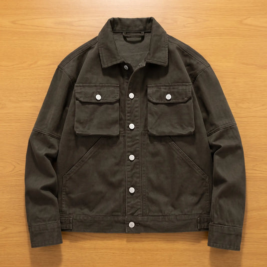 Army green heavy canvas trucker jacket laid flat on an oak workbench