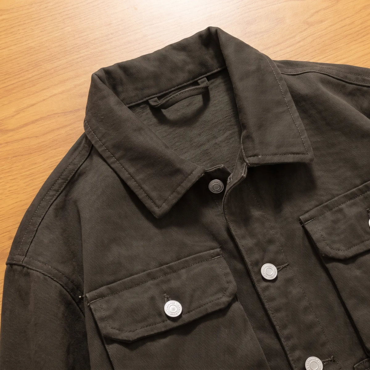 Close up of the collar, chest flap pocket and shank buttons on the army green canvas trucker jacket