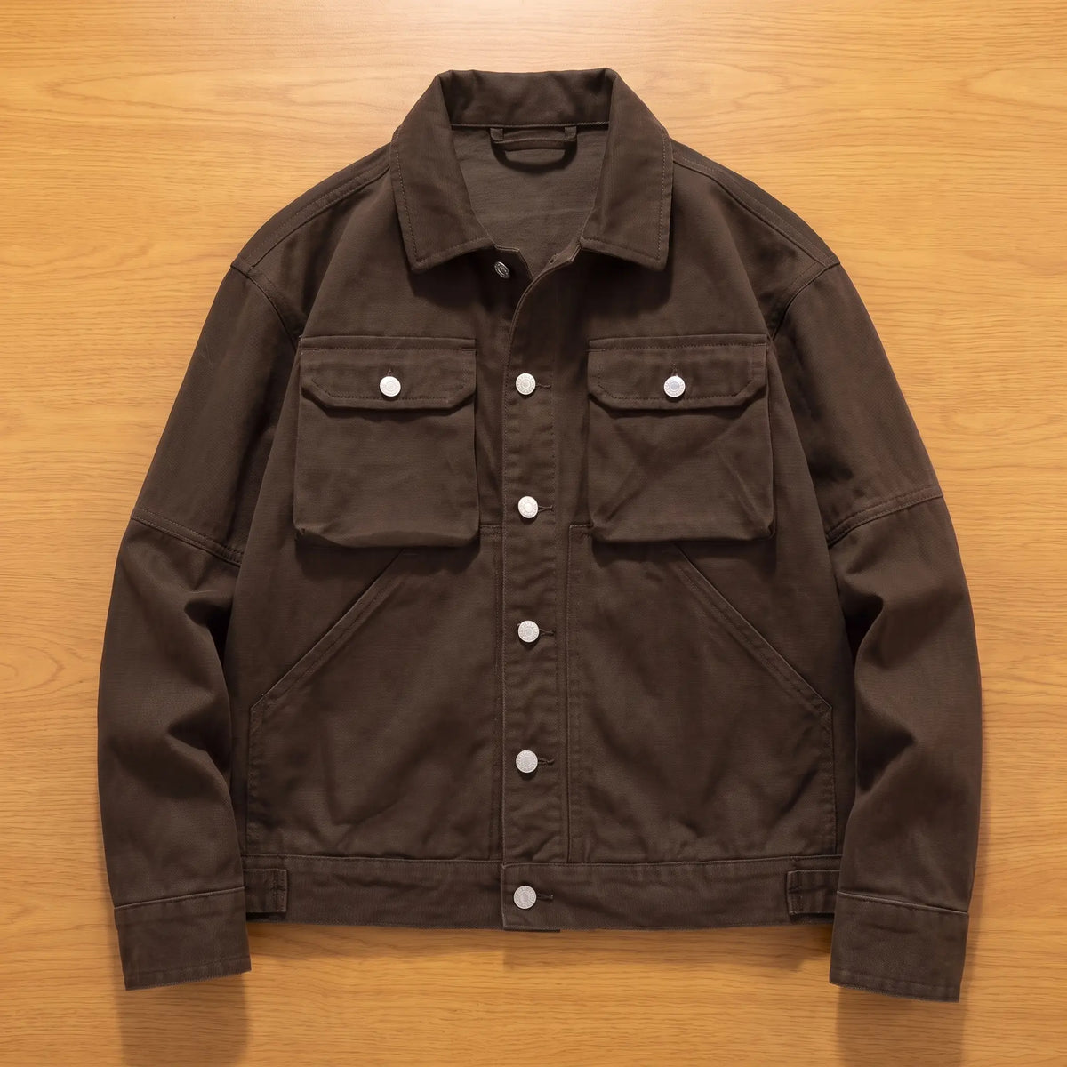 Coffee brown heavy canvas trucker jacket laid flat on an oak workbench