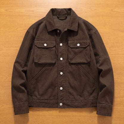 Coffee brown heavy canvas trucker jacket laid flat on an oak workbench