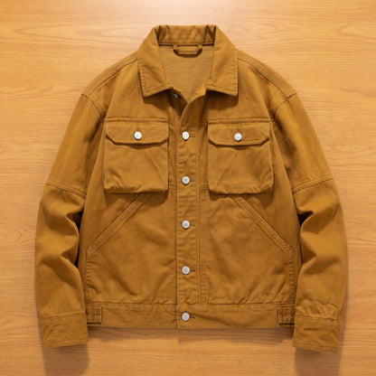 Khaki heavy canvas trucker jacket laid flat on an oak workbench