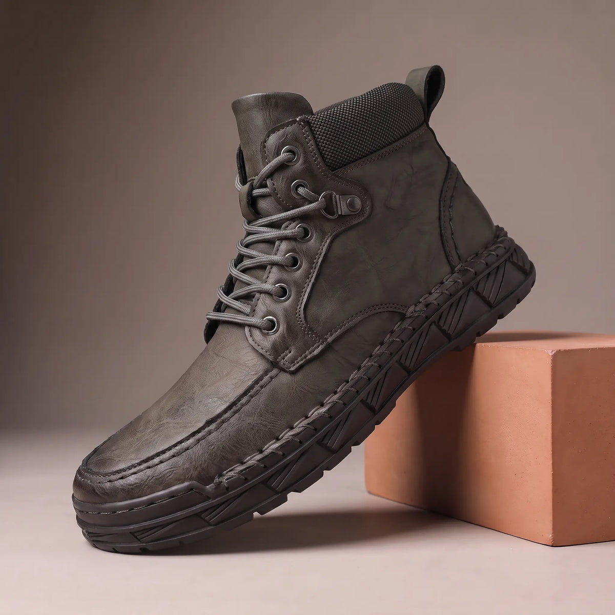 Gray heavy lug moc toe boot on a terracotta display block