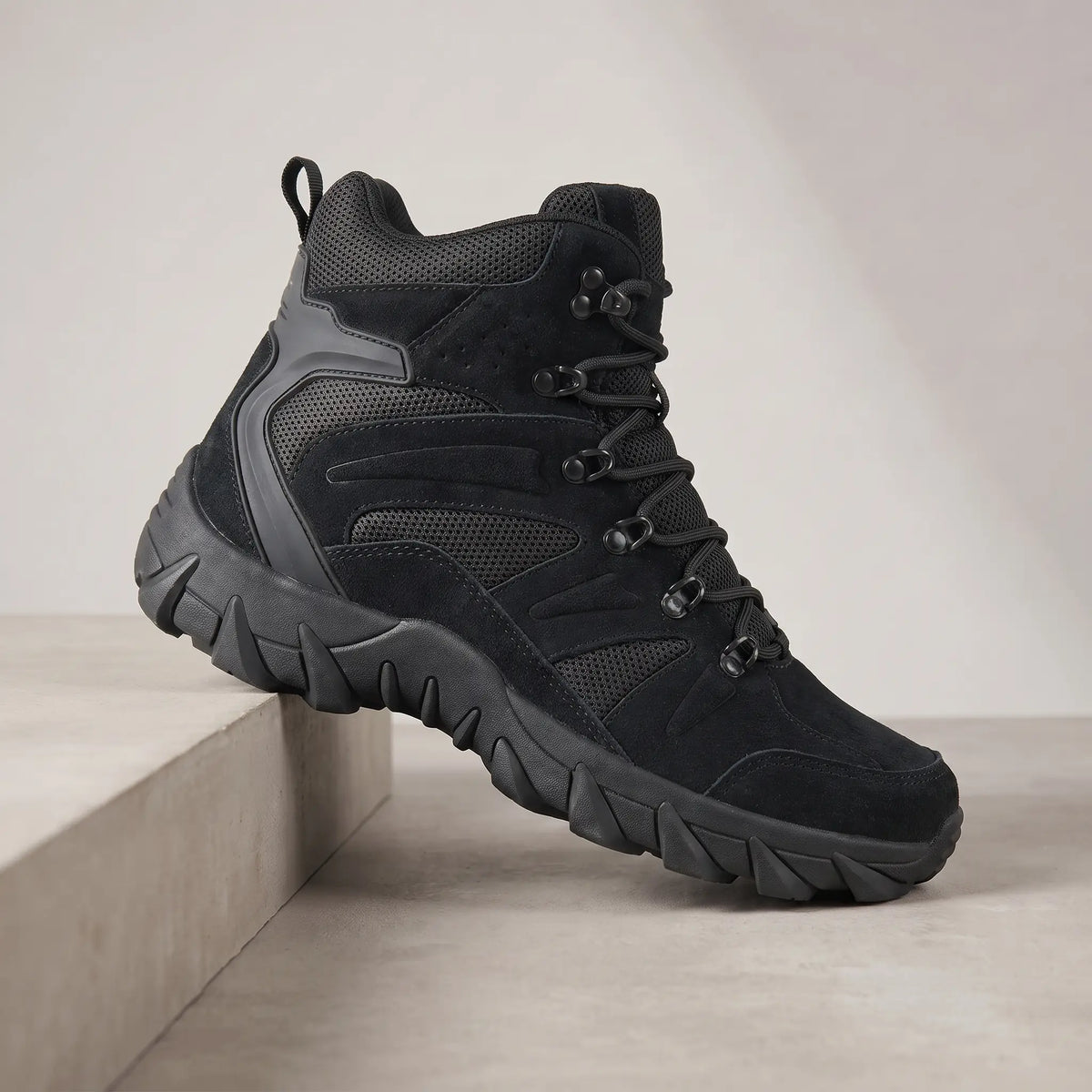 Black high-top tactical boots for men, suede lace-up boot on a concrete plinth