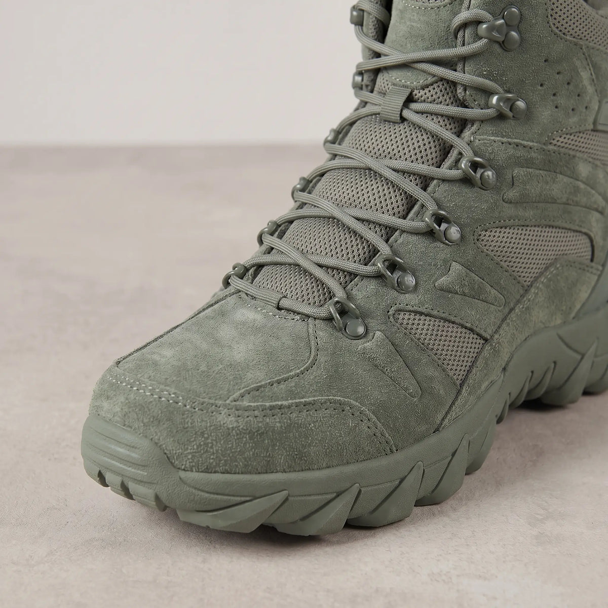 Close-up of the lacing and speed hooks on green high-top tactical boots for men