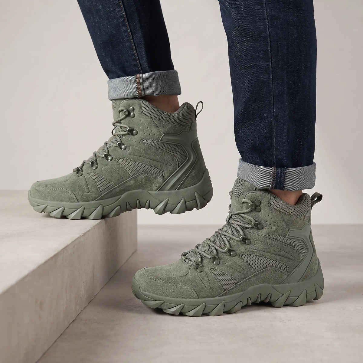 Man wearing green high-top tactical boots with cuffed jeans on a concrete step