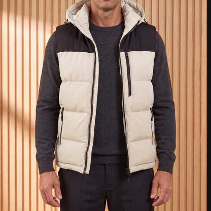 Men's cream hooded puffer vest with black yoke, worn open over a charcoal knit