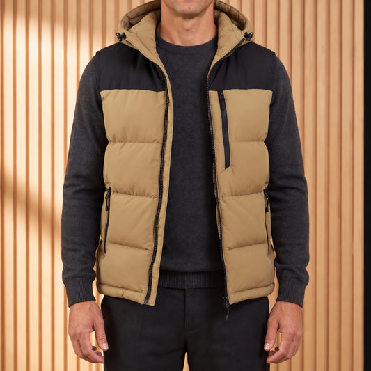 Men's khaki hooded puffer vest with black yoke, worn open over a charcoal knit