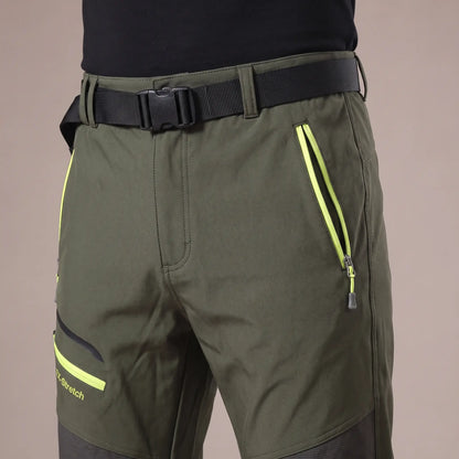 Close-up of green hiking trousers waistband with webbing belt and zip pockets