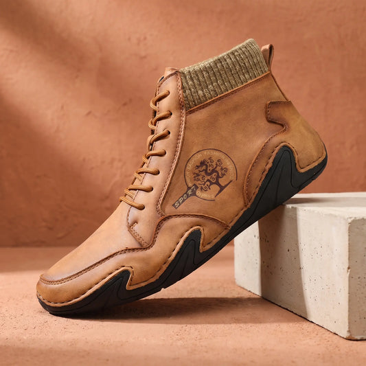 Men's brown stitched leather ankle boot with knit collar on a concrete plinth