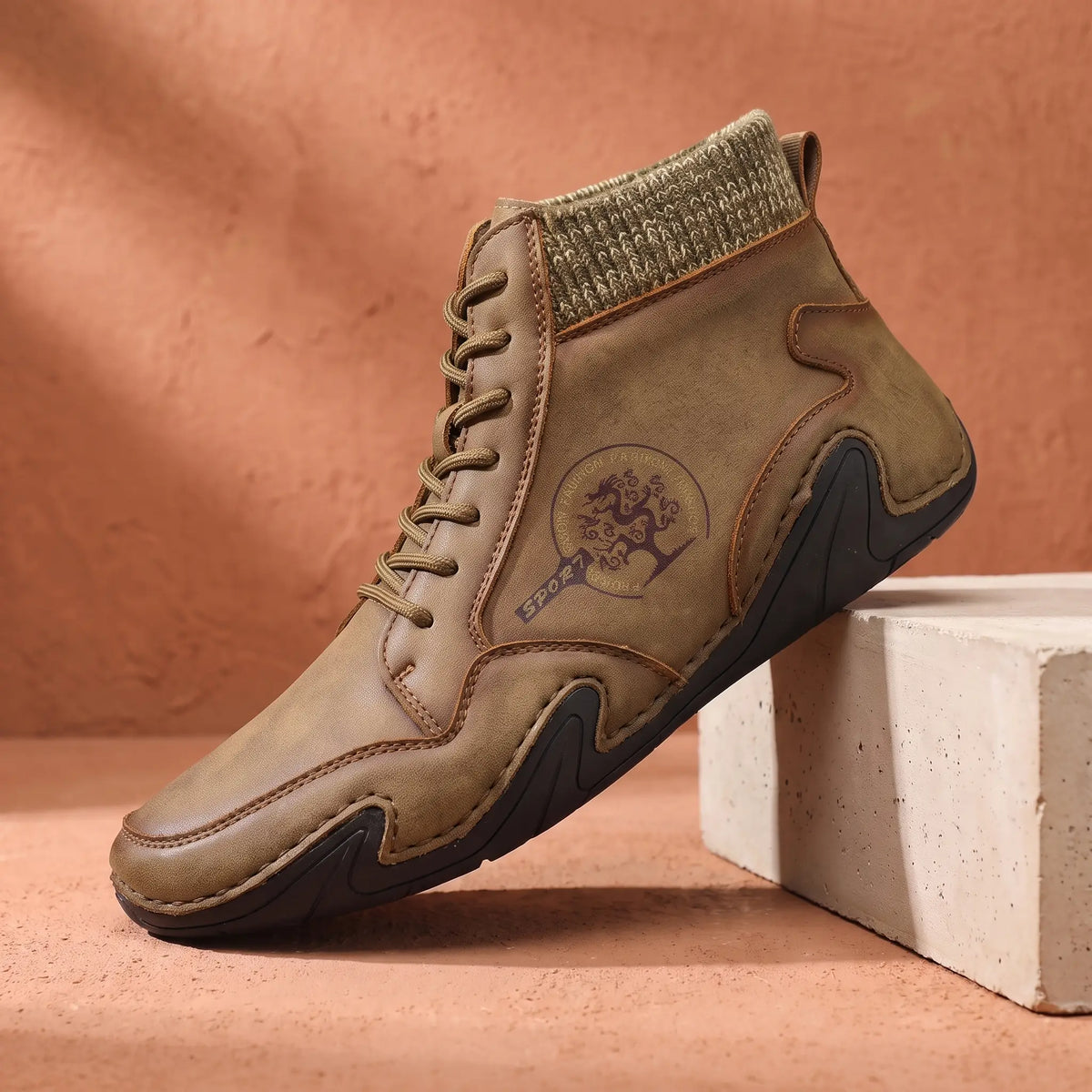 Men's khaki stitched leather ankle boot with knit collar on a concrete plinth