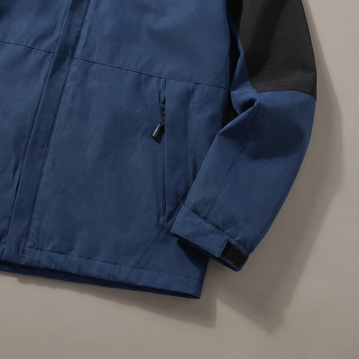 Close up of the zip hand pocket and adjustable cuff tab on the navy blue layered hooded jacket