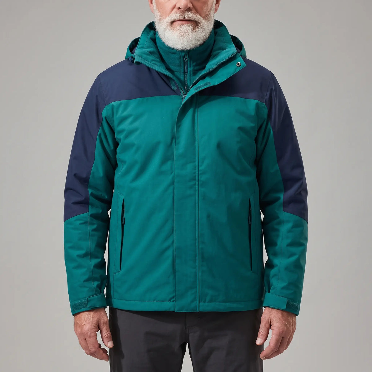 Men's green hooded shell jacket with navy blue shoulder panels and a zip-in fleece, worn zipped
