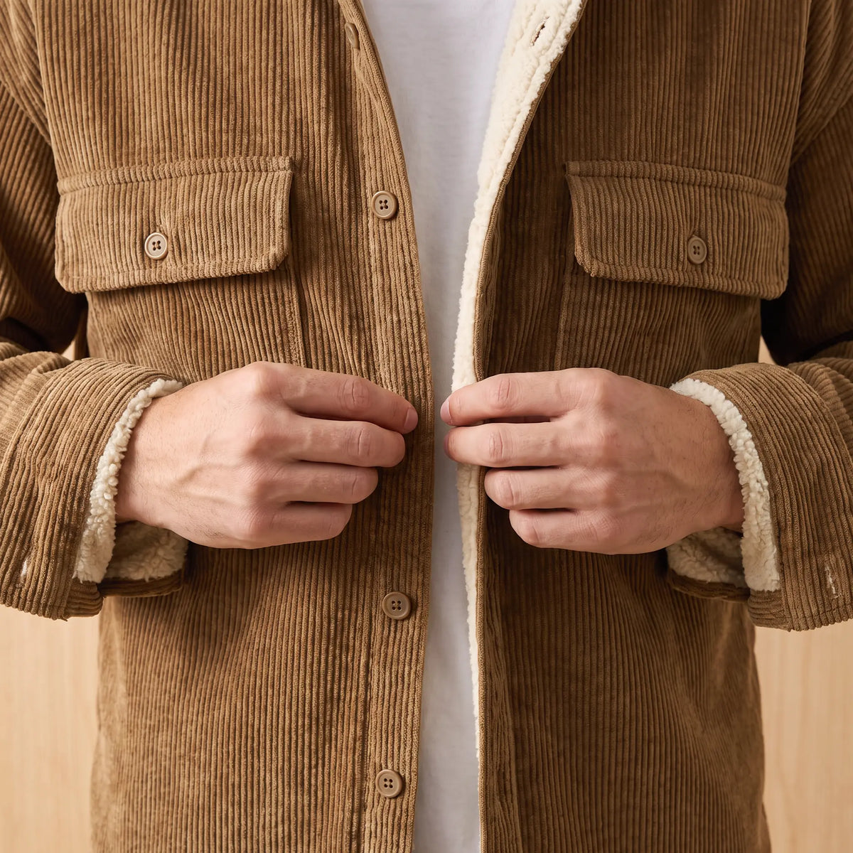 Man buttoning up the khaki Layering Shirt Jacket worn over a white tee