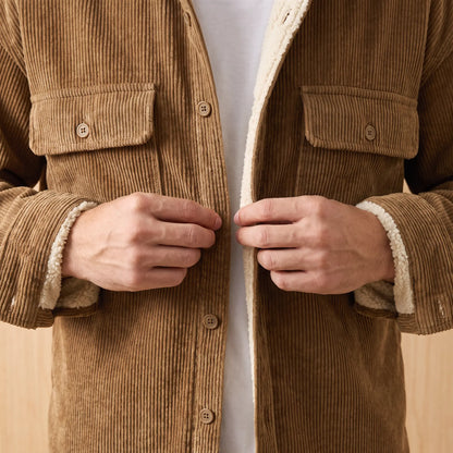 Man buttoning up the khaki Layering Shirt Jacket worn over a white tee