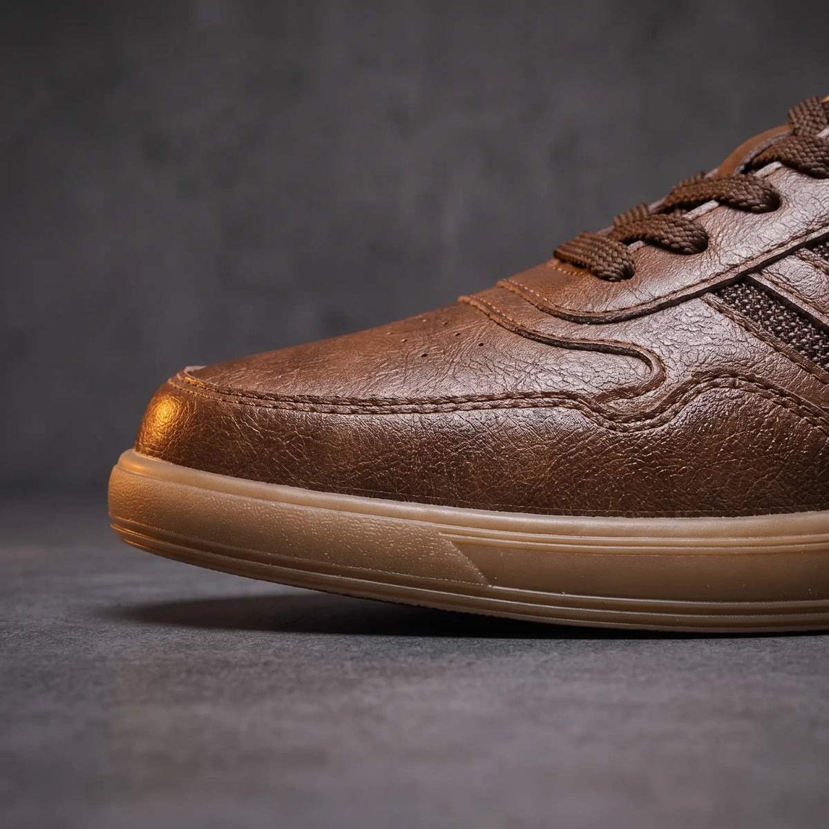 Front close up of brown court sneakers showing the perforated wingtip toe seam