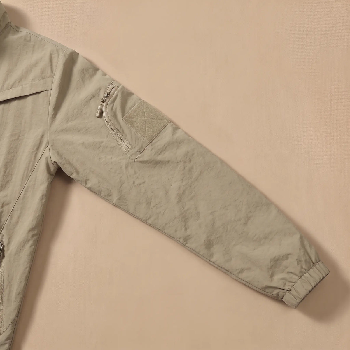 Close-up of the sleeve zip pocket and patch panel on the khaki utility jacket