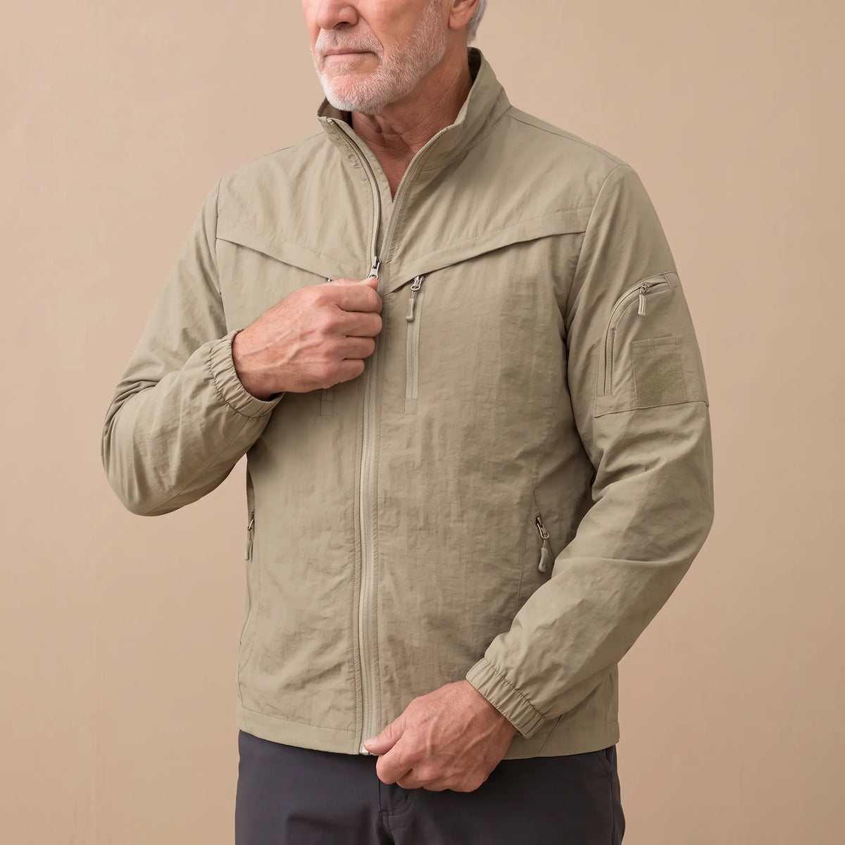 Man wearing the khaki lightweight utility jacket, drawing the zip up
