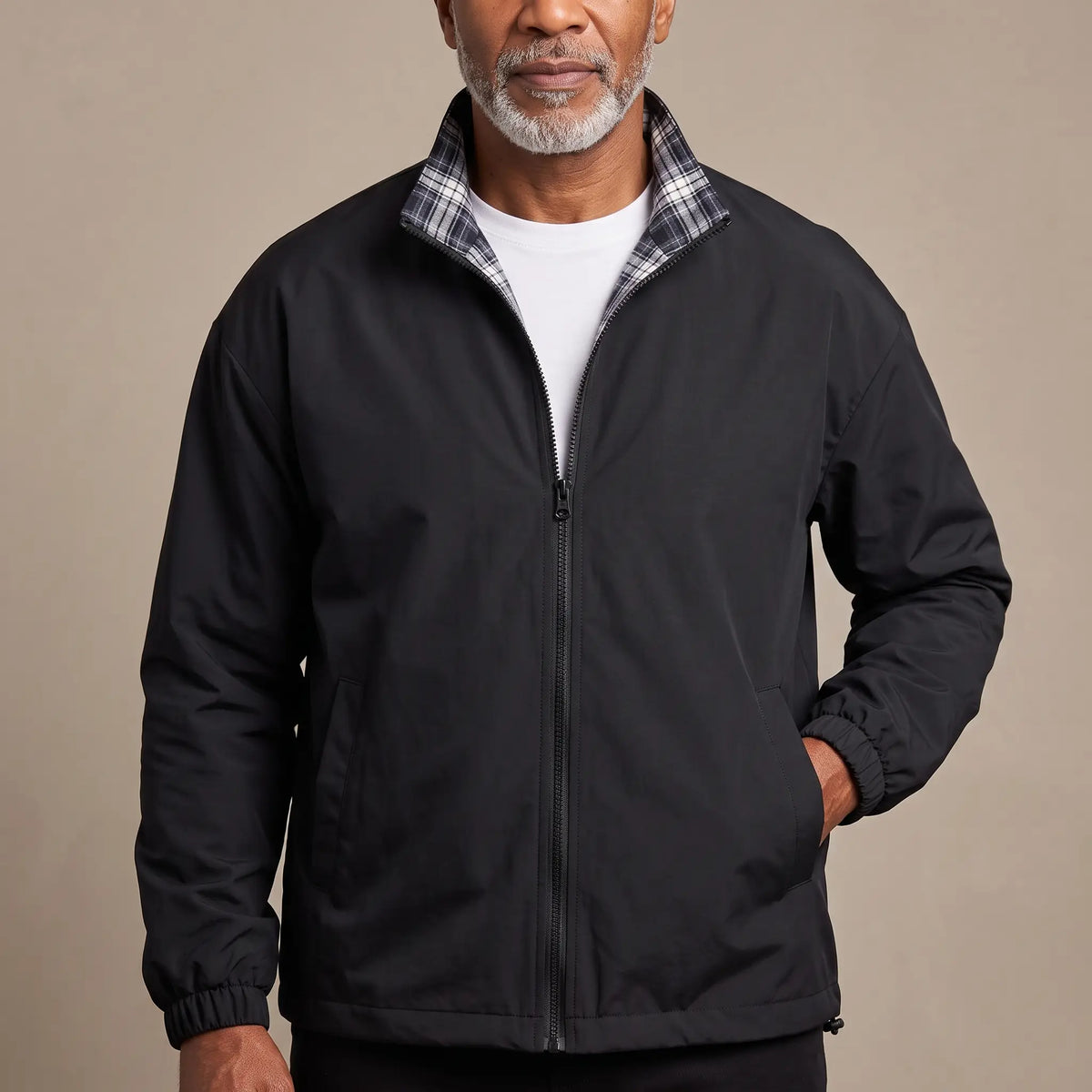 Man wearing the LIGHT REVERSIBLE JACKET in black with a plaid-lined stand collar