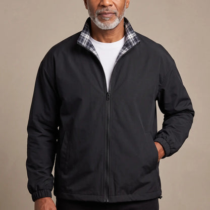 Man wearing the LIGHT REVERSIBLE JACKET in black with a plaid-lined stand collar