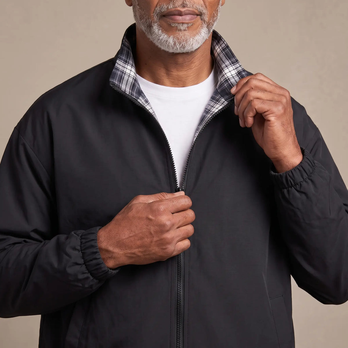Man zipping up the LIGHT REVERSIBLE JACKET in black