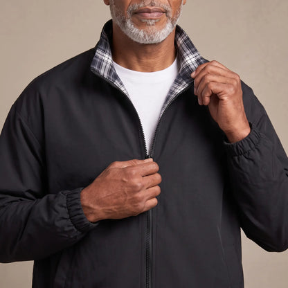 Man zipping up the LIGHT REVERSIBLE JACKET in black