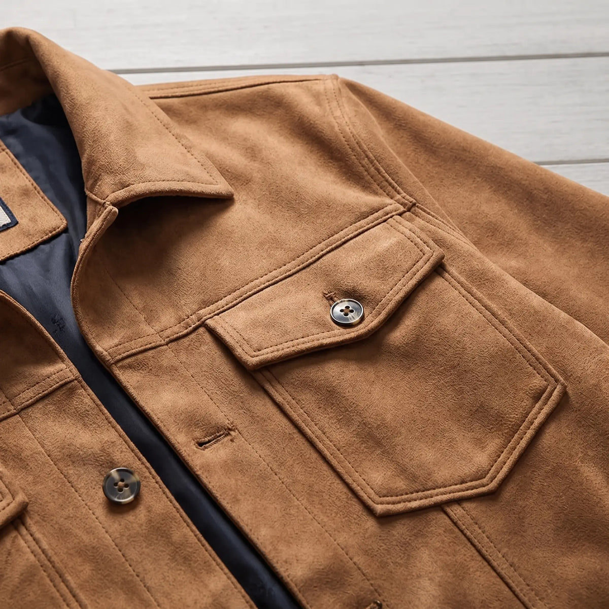 Close up of the pointed collar, front buttons and shield shaped chest pocket flap on the tan lined trucker jacket