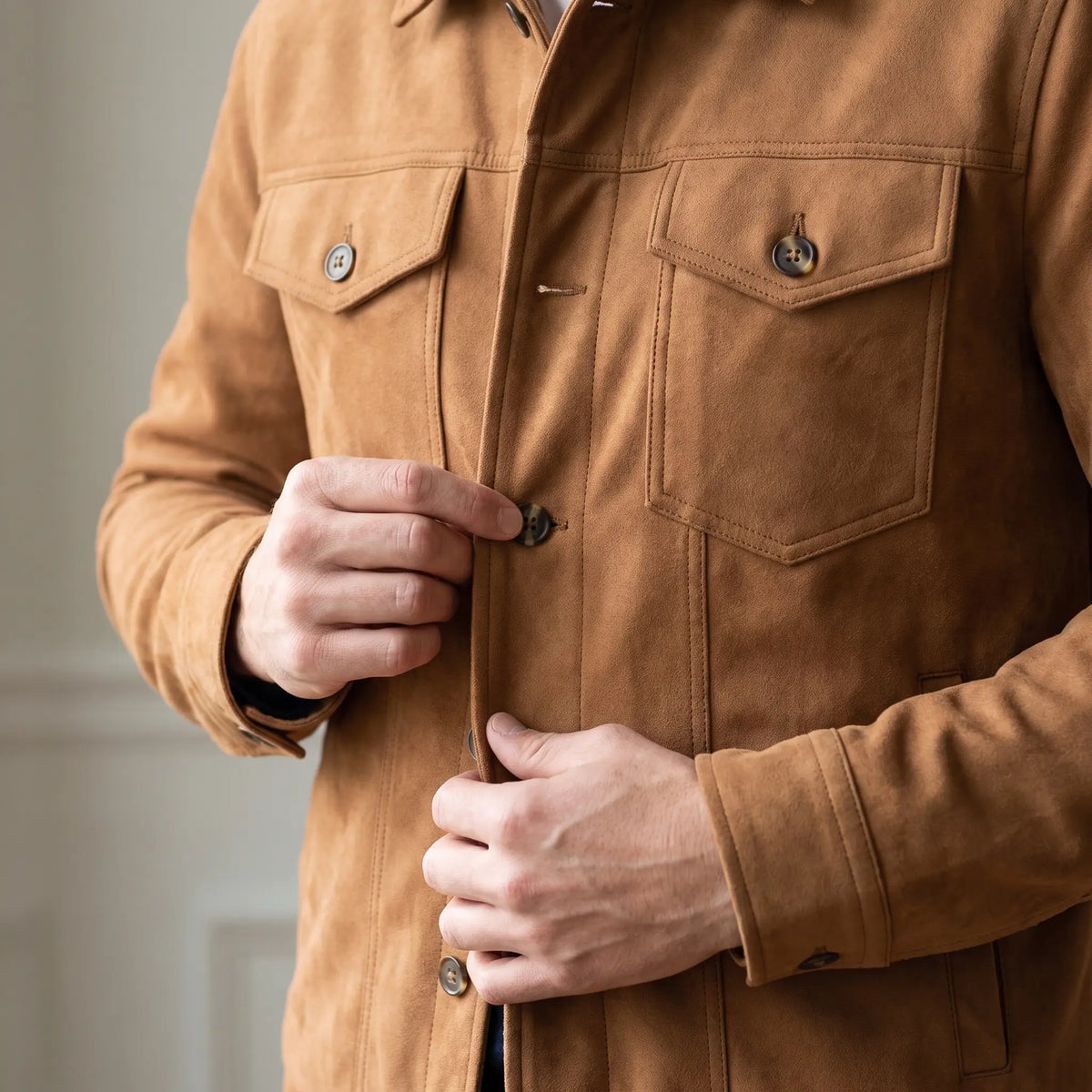Man fastening a front button on the tan lined trucker jacket worn over a tee