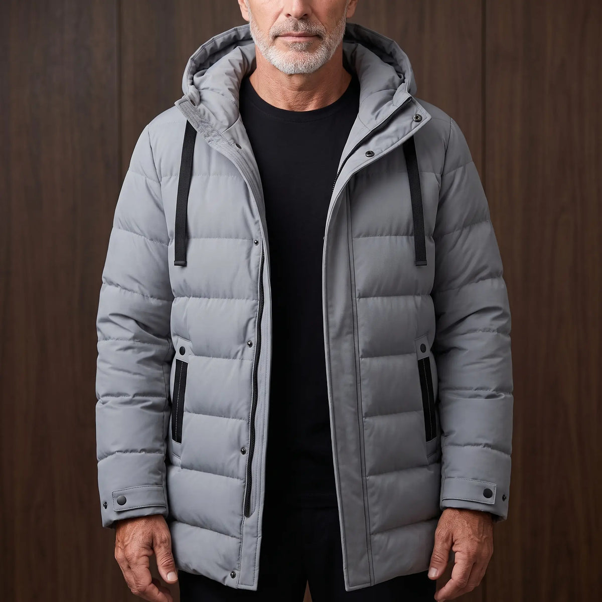Men's grey long hooded puffer coat with quilted padding, worn open over a black tee