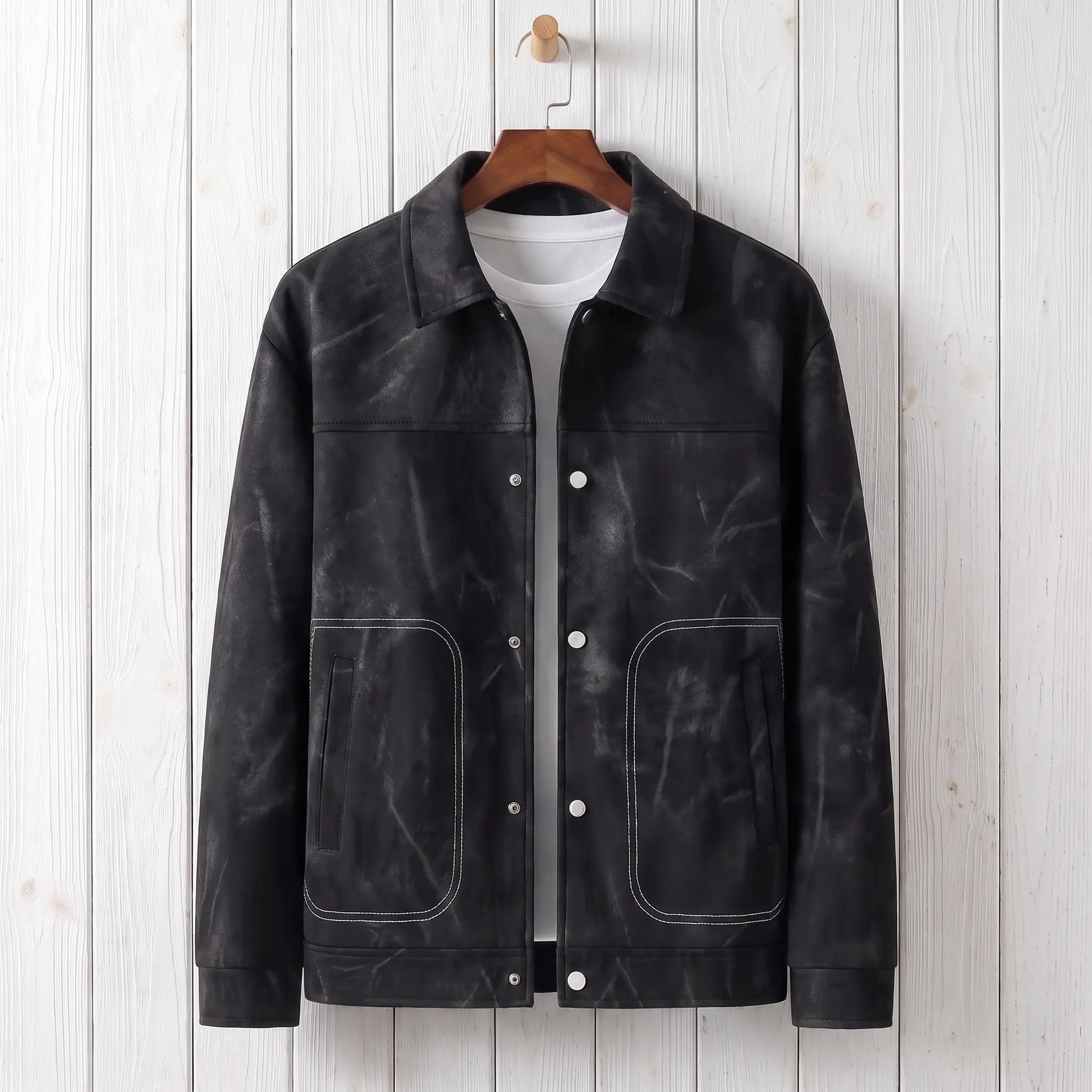 Black marbled dye trucker jacket on a wooden hanger against a whitewashed plank wall