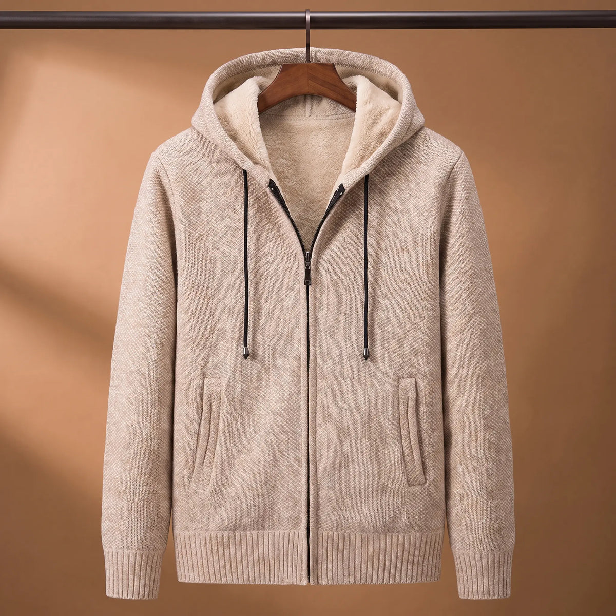 Marled knit hoodie in beige with fleece-lined hood on a wooden hanger