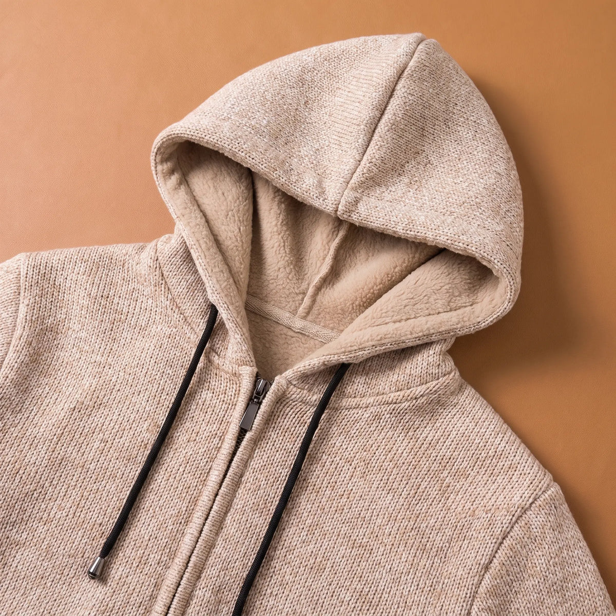Close-up of the beige marled knit hoodie lined hood, drawcords and zip